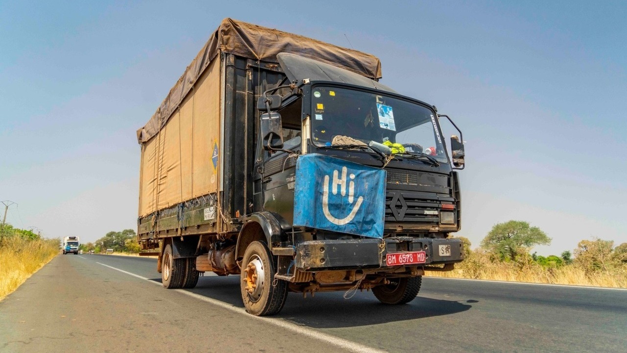 A truck drives along a road with an HI flag on its hood.