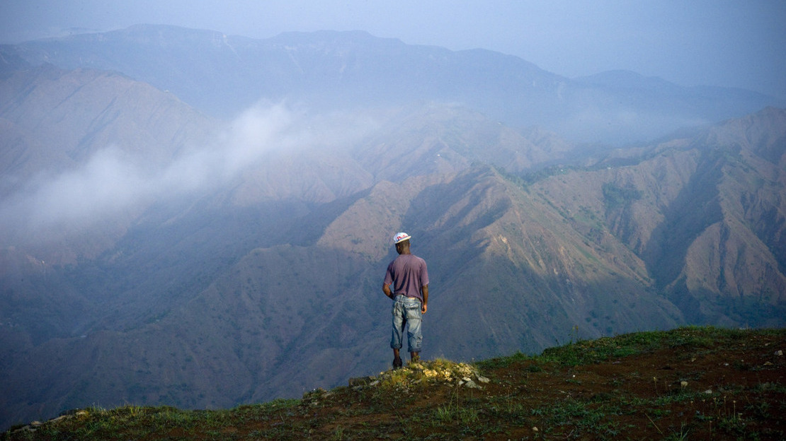 A man stands with his back to us, staring into the distance: behind him, a grandiose landscape of mountains in mist.