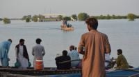 A young man stands in front of the floodwaters.