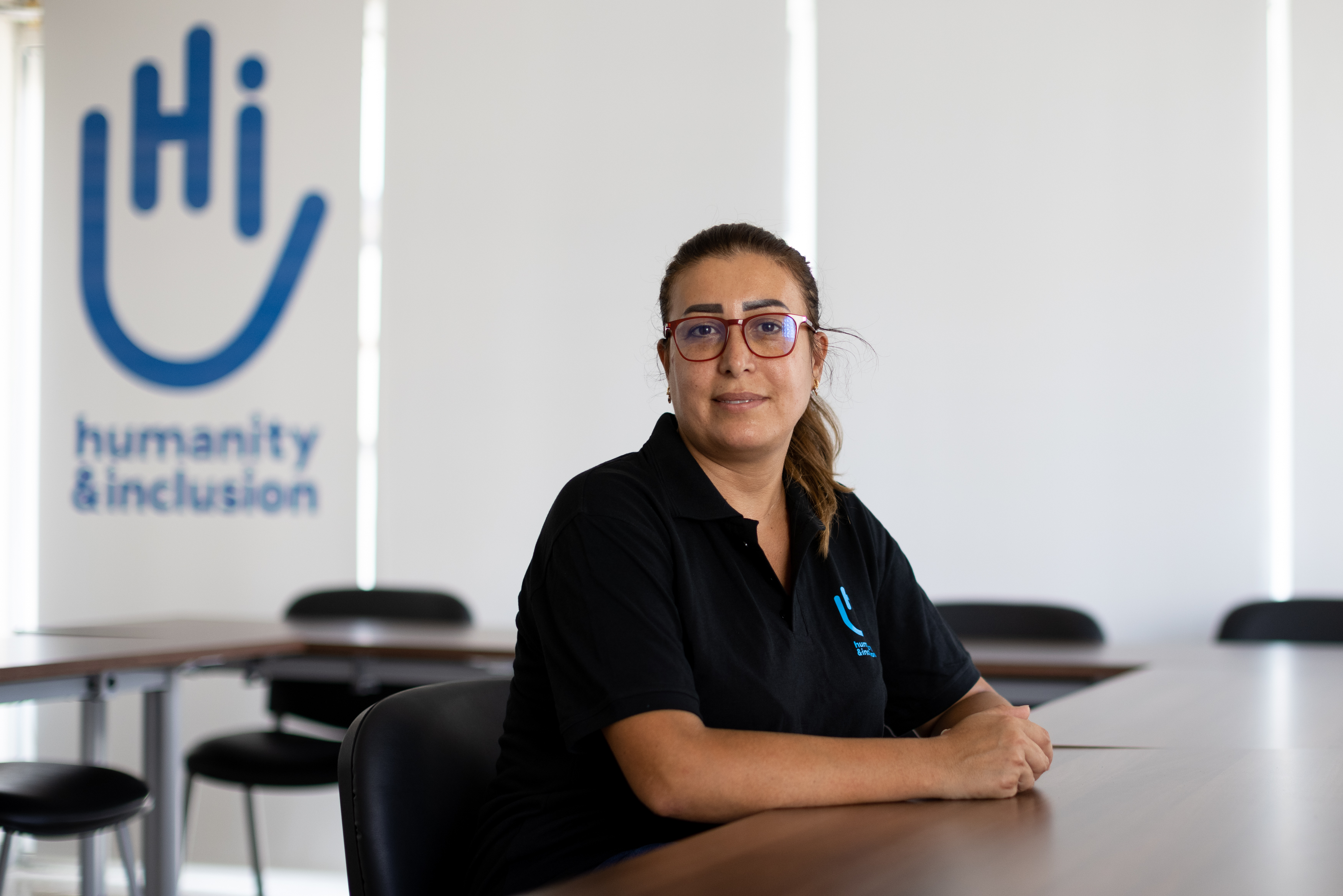 HI Operations Manager Zeina Salhani sits at a table with the HI logo in the background